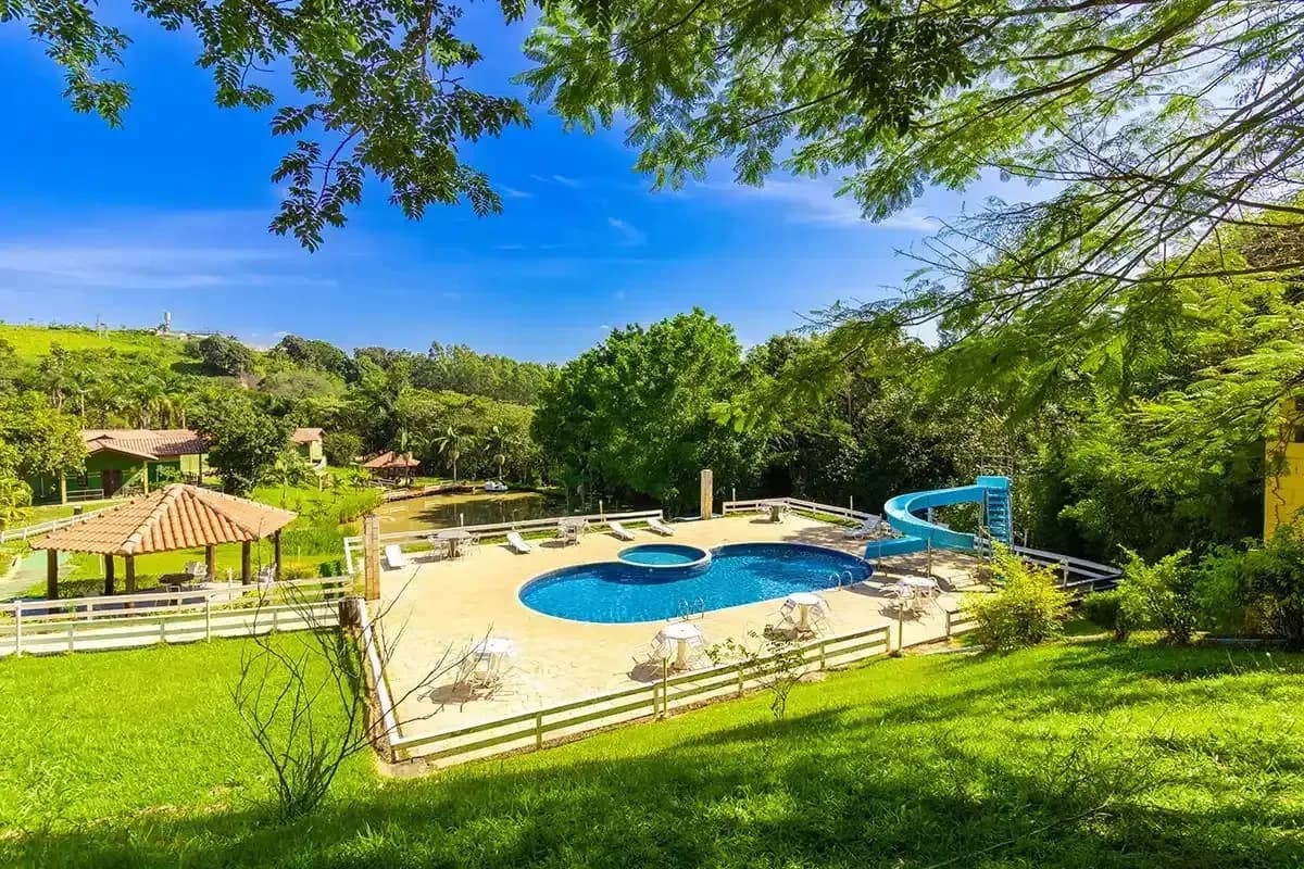 Piscina externa com tobogã do Portal dos Sonhos, cercada de área verde